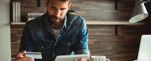 Man holding credit card while pondering penalty apr, trying to figure out what is penalty apr.