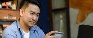 Man holding credit card in front of his laptop
