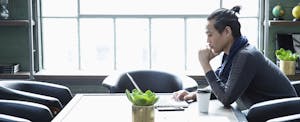 Businessman using laptop in a modern office, looking serious