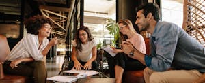 Group of four coworkers sitting together and talking