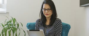 Young woman in glasses looking at her digital tablet at home to look up sr-22 insurance