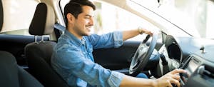 Man turning on the radio in his car that he insured with amica auto insurance