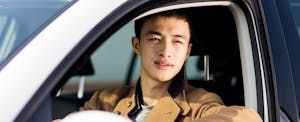 Man driving his car, looking out the window with a thoughtful expression as he considers using Direct Auto Insurance