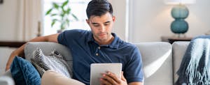 auto-loan-chargeoff-without-repossession Man sitting at home, looking up auto loan chargeoff without repossession on his digital tablet
