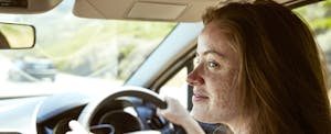 Smiling young woman in car looking sideways out the window