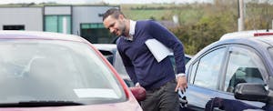 Man looking into a car for sale on a dealership lot, wondering if he can buy a car with a credit card