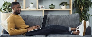 discount-car-insurance-guide_1164339557 Man using a laptop on the couch while relaxing at home
