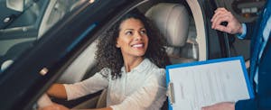 tesla-insurance-review_913442484 Woman smiles while considering the option of Tesla Insuurance.