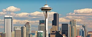 City skyline of downtown Seattle during the day, blue sky and clouds in the background, with the space needle front and center