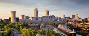cheapest-places-to-travel-us The downtown Cleveland skyline at dusk with the Cuyahoga River in the foreground.
