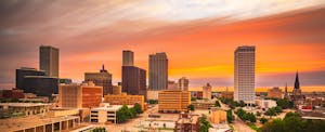 tulsa-debt-statistics The Tulsa, Oklahoma, downtown skyline against an orange hued sky at twilight