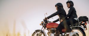 Young couple taking a break while riding a vintage motorcycle through the countryside