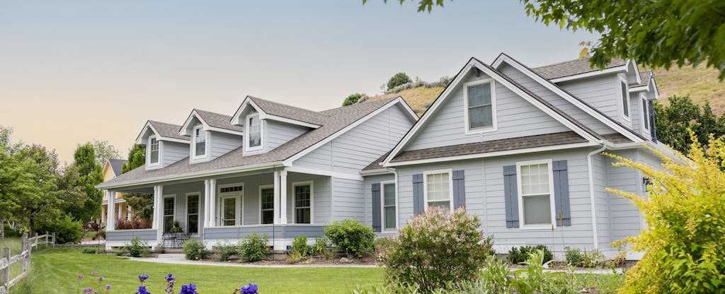 Suburban home exterior at sunset with lawn and garden visible
