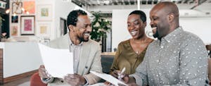 Couple sits at a table with mortgage broker discussing refinancing.